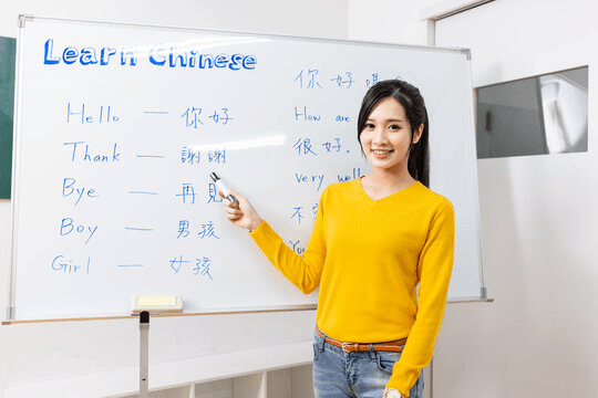 Chinese tutor teaching vocabulary at a whiteboard